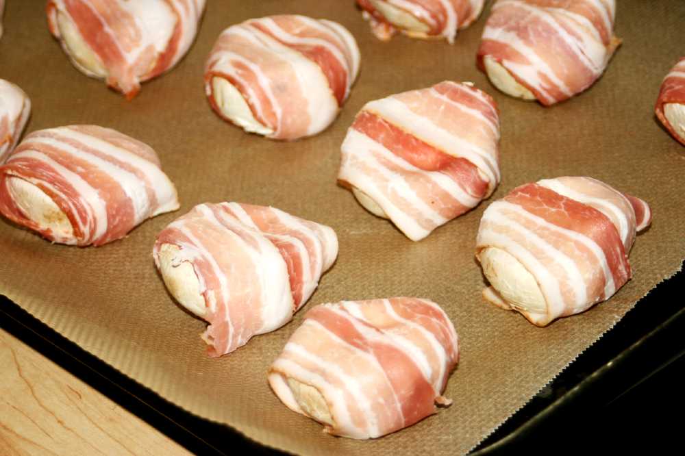 Champinjoner inlindade i bacon på en bakplåt med bakpapper.
